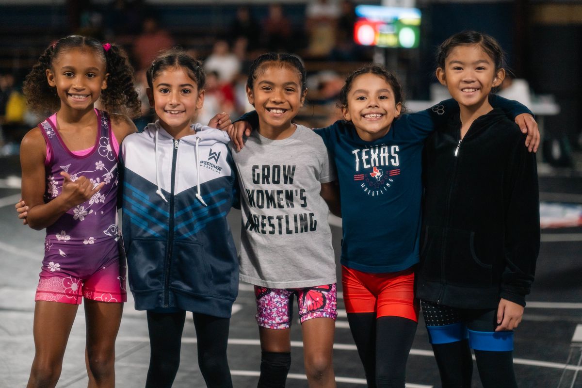 Smiling young girl wrestlers in Texas and Grow Women's Wrestling shirts