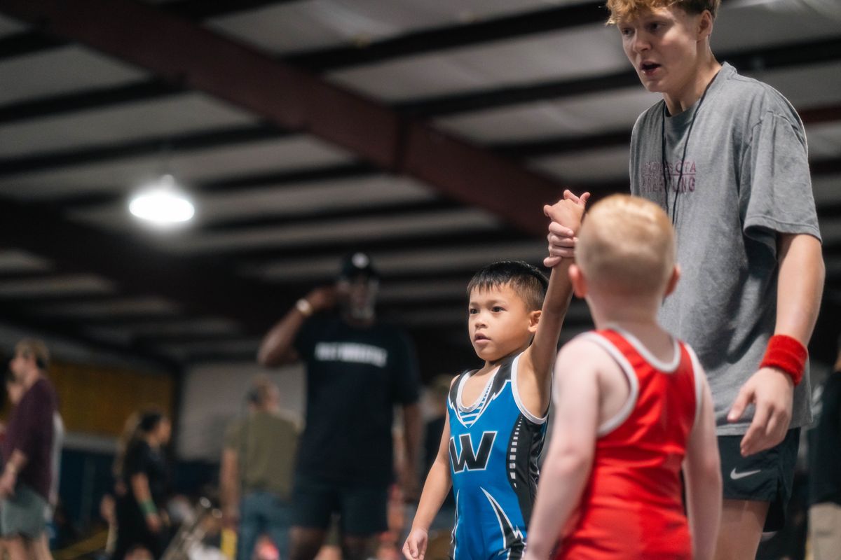 A young wrestler raises his hand after winning a match